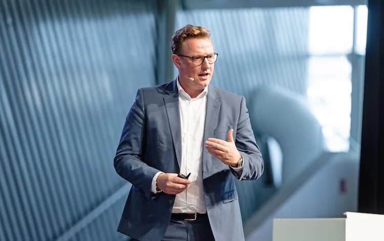 Mann im Anzug hält Präsentation auf Bühne