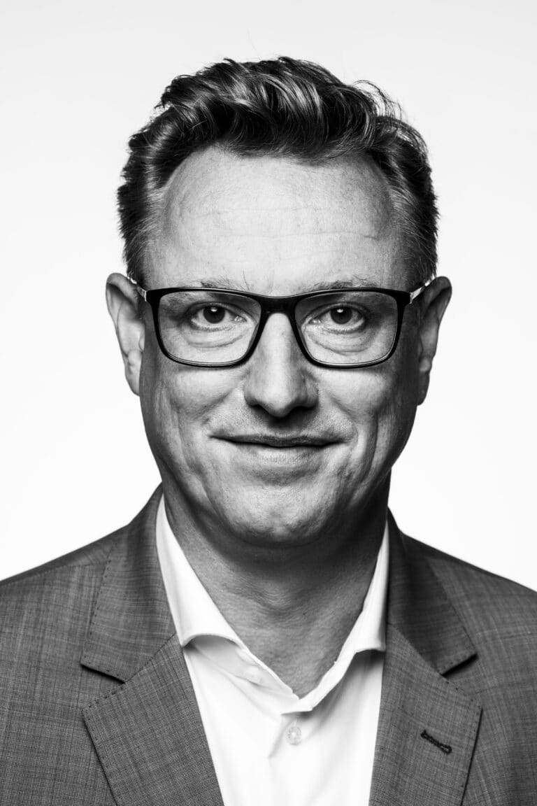 Schwarzweiß-Porträt eines Mannes mit Brille im Anzug